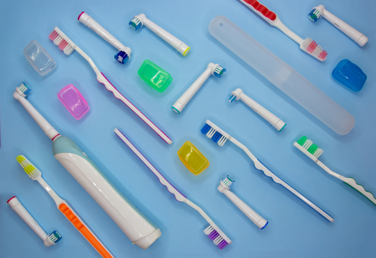 Elektriske tannbørster og vanlige tannbørster mot blå bakgrunn. Foto